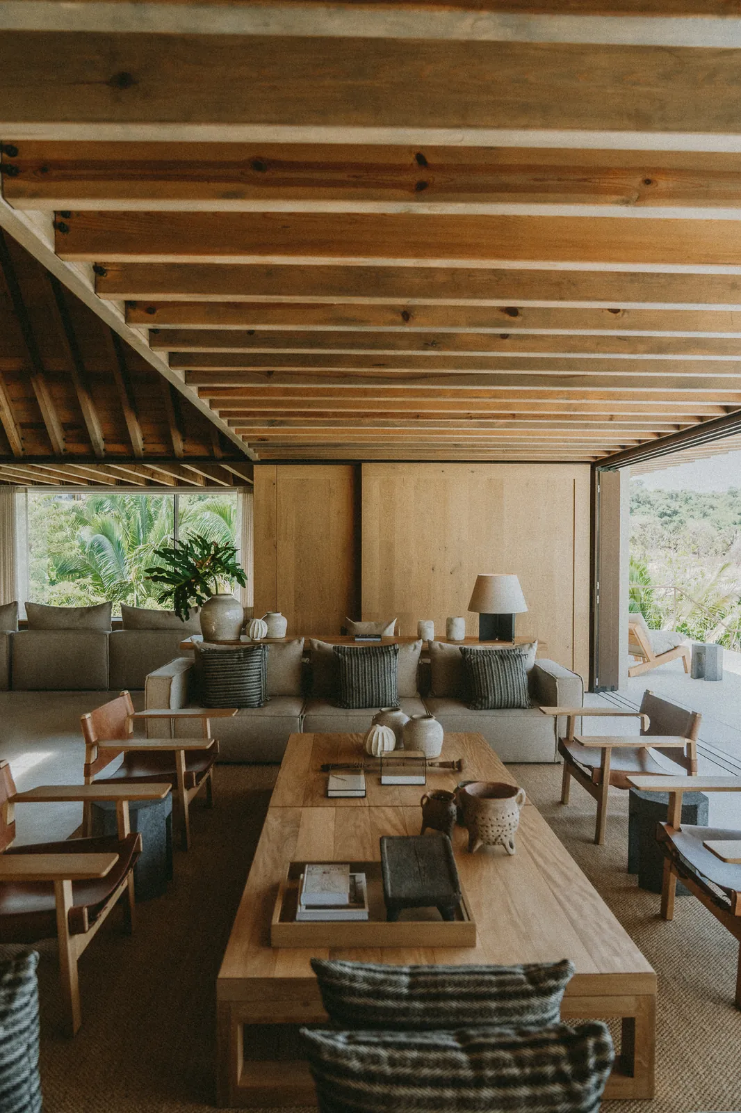 The living room: deep sofas, leather-slung armchairs and a long low wooden table under the beamed ceiling