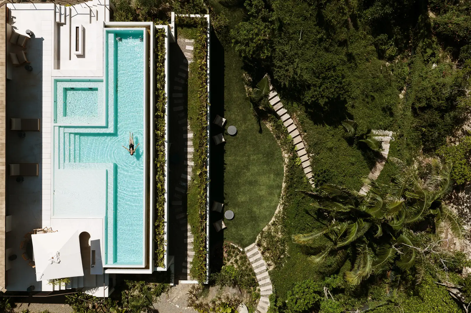 The pool and terrace from directly above, beside the lawn and stepping-stone paths curving down through the garden